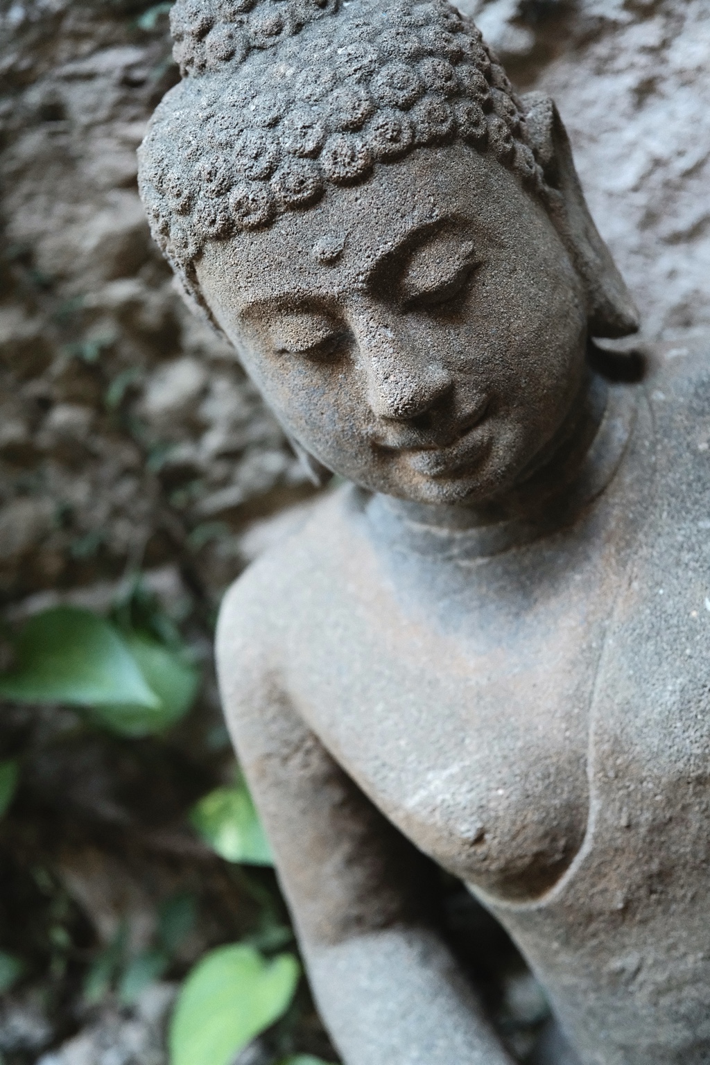 A weathered garden sculpture among green leaves