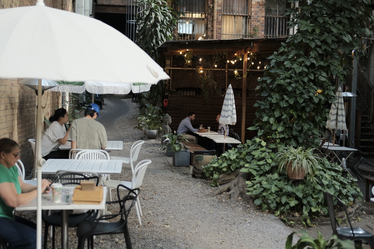 Guests seated beneath a white courtyard umbrella